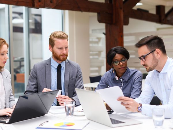 Group of business people is working on new business strategy with a financial analyst while analyzing financial chart during meeting in the office.